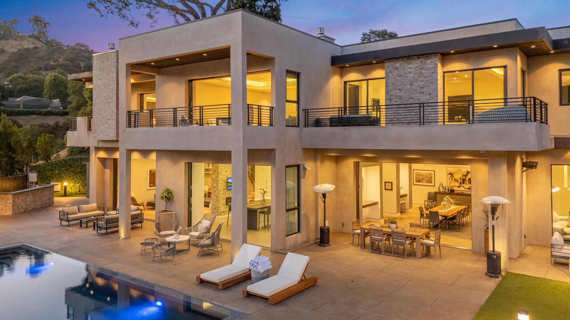 Both levels of the villa lit warm at blue hour